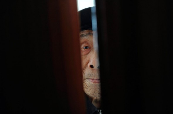 An elderly man peers from a door in a nursing home in Hefei, Anhui province in China.
